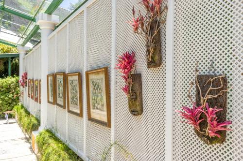 a wall with paintings and flowers in vases on it at Locanda della Mimosa in Itaipava