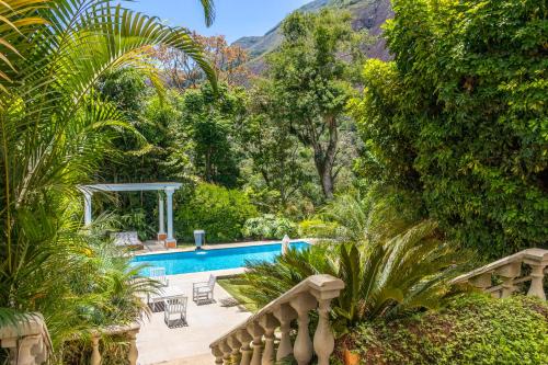 a swimming pool in the middle of a garden at Locanda della Mimosa in Itaipava