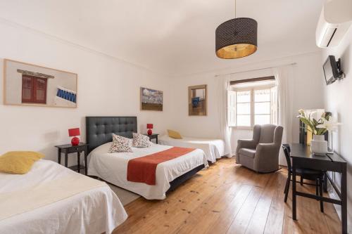 a hotel room with two beds and a desk at Burgos Guest House in Évora