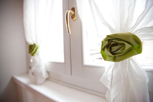 a green rose on a window with a white curtain at Appartamenti LEON D'ORO in Riva del Garda