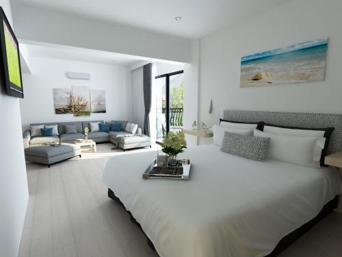 a white bedroom with a large bed and a living room at Gokcen Hotel & Apartments in Oludeniz