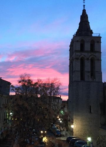 a building with a tower with a sunset in the background at JOHA DOMA in Lunel