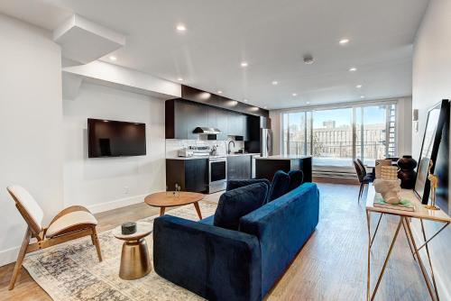a living room with a blue couch and a kitchen at Burgundy Lofts - Marché Atwater in Montréal