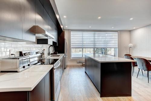 a kitchen with stainless steel appliances and a large window at Burgundy Lofts - Marché Atwater in Montréal