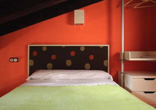 ein Schlafzimmer mit einem Bett mit einer orangefarbenen Wand in der Unterkunft Los Masecicos in Mora de Rubielos