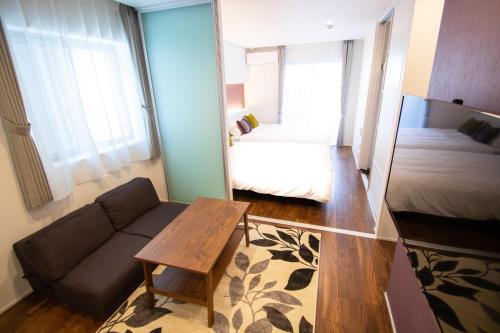 a living room with a couch and a bed and a mirror at Apartment Hotel Tenjin TUMUGU / Vacation STAY 62166 in Susakiuramachi