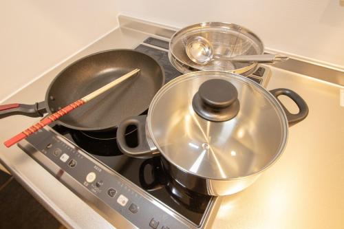 a stove top with pans and utensils on it at Apartment Hotel Tenjin TUMUGU / Vacation STAY 62178 in Susakiuramachi