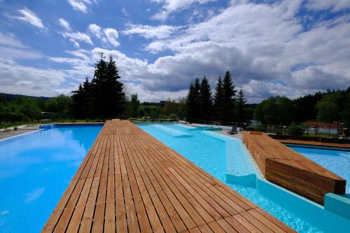 a large swimming pool with a wooden deck at Lipno-Frymburk Wellnes APT D 103 in Frymburk