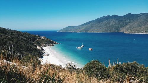 vistas a una playa con un barco en el agua en Suíte praia dos Anjos, en Arraial do Cabo