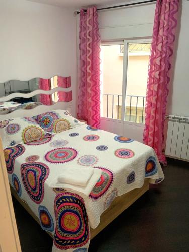 a bedroom with a bed with a colorful blanket and a window at Apto Arima Centro Histórico in Zaragoza