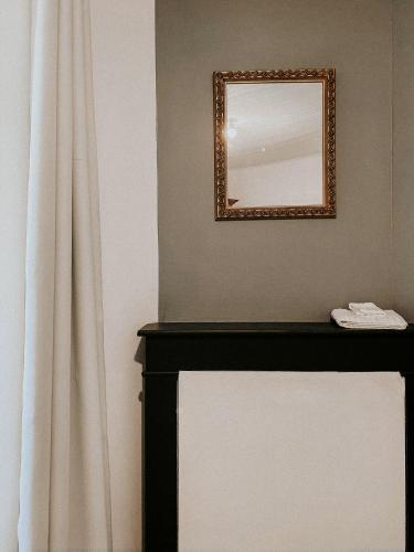 a mirror on a wall next to a fireplace at Le Val Suzenay in Vendeuvre-sur-Barse