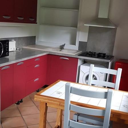 kuchnia z czerwonymi szafkami oraz stołem i krzesłami w obiekcie maison xemartea w mieście Hasparren