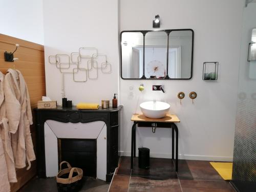 a bathroom with a sink and a mirror and a fireplace at Le 43-4 avec sauna privatif in Le Puy-en-Velay