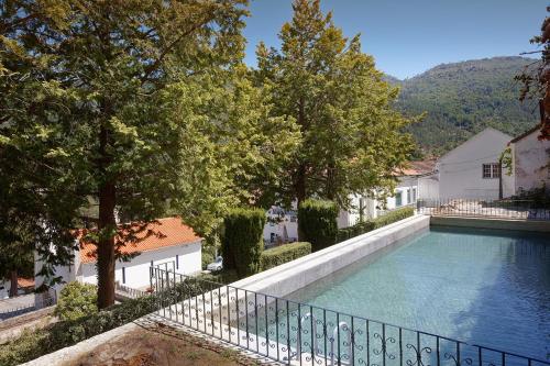 a swimming pool with a fence next to a house at Casa do Comendador in Manteigas