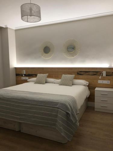 a bedroom with a bed with two mirrors on the wall at Apartamento Abuelo Mayorga in Plasencia