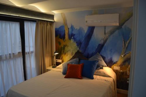 1 dormitorio con 1 cama con una pintura en la pared en DUPLEX ALAMEDA DE HERCULES en Sevilla
