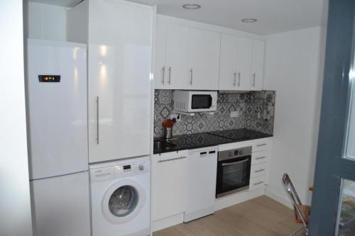 a kitchen with white cabinets and a washer and dryer at DUPLEX ALAMEDA DE HERCULES in Seville