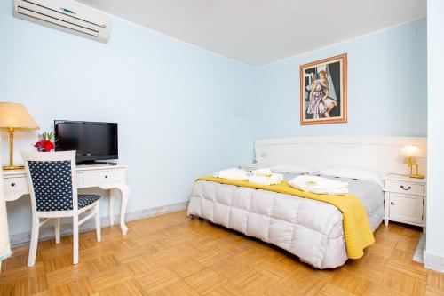 a bedroom with a bed and a desk and a television at Hotel Marini in Sassari