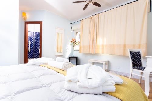 two beds in a white room with a ceiling fan at Hotel Marini in Sassari