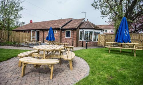 a group of picnic tables and blue umbrellas in a yard at Hotel 52 Stanley in Stanley