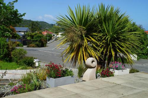 a statue of a swan in a garden with a palm tree at A Touch of Class in Greymouth