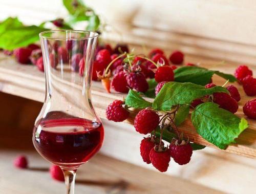 a glass of red wine next to a bunch of raspberries at Malinovy Sen II in Habovka