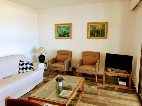 a living room with a couch and two chairs and a tv at Parquemar Center PRIMERA LINEA FRENTE AL MAR Piso 8 LOS DEDOS Garage y amenities in Punta del Este