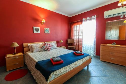 een slaapkamer met rode muren en een bed in een kamer bij Villa Lídia in Armação de Pêra