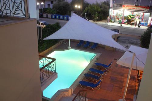 una piscina con sedie e un grande ombrellone bianco di Vicky Apartments a Nikiana