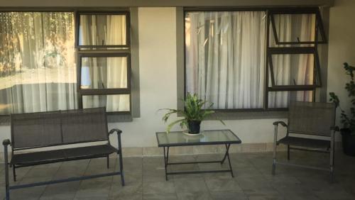 two chairs and a table in a room with windows at Cheryl's Fortress in Johannesburg