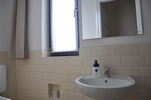 a bathroom sink with a bottle of soap on it at Centrál Vendégház Székesfehérvár in Székesfehérvár
