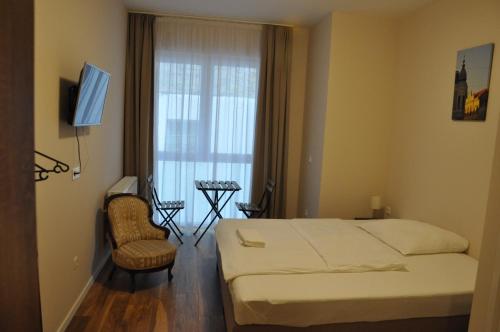 a bedroom with a bed and a chair and a window at Centrál Vendégház Székesfehérvár in Székesfehérvár
