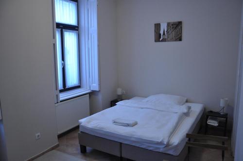 a small white room with a bed and a window at Centrál Vendégház Székesfehérvár in Székesfehérvár