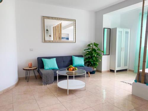 a living room with a blue couch and a table at Hibiscus Studio in Corralejo