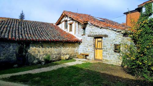 una antigua casa de piedra con una puerta de madera en un patio en La plazuela verde, en Atapuerca