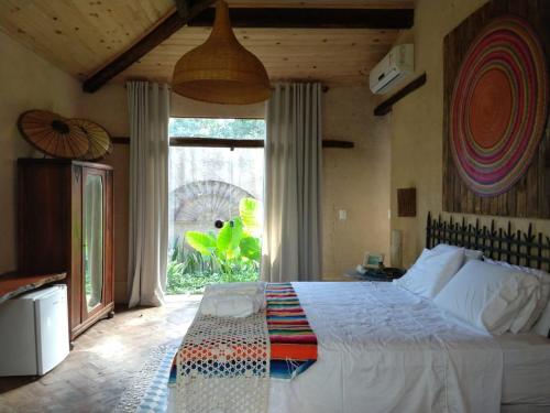 a bedroom with a large bed and a large window at Zazen Pousada by Santoregano in Maceió