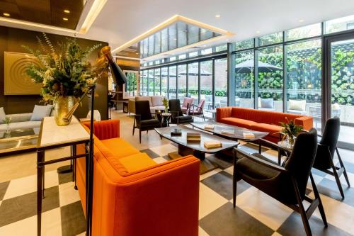 a restaurant with orange chairs and tables and windows at Hyatt Centric Las Condes Santiago in Santiago