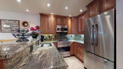 a kitchen with wooden cabinets and a stainless steel refrigerator at Enzian - CoralTree Residence Collection in Vail