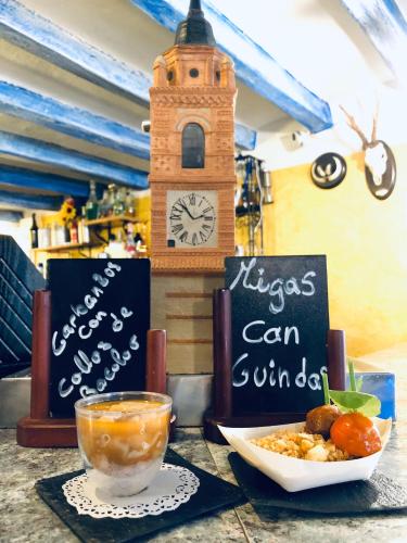 a table with a bowl of food and a clock tower at Hostal El Bodegon in Ateca
