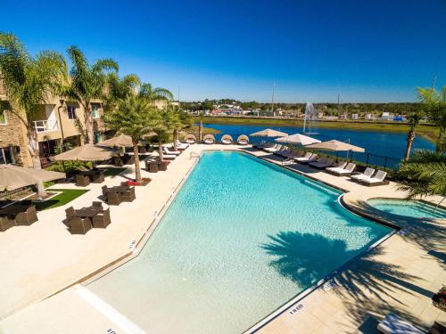 a large swimming pool with chairs and umbrellas at Magic Village Yards Trademark Collection by Wyndham in Orlando