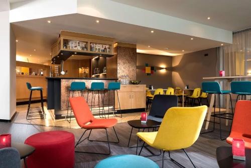 restauracja z kolorowymi krzesłami i bar w obiekcie Ramada by Wyndham Hannover w Hanowerze