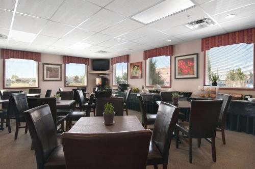 a dining room with tables and chairs and windows at Travelodge by Wyndham Stony Plain in Stony Plain