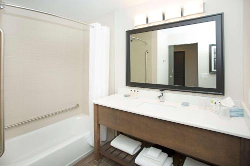 a bathroom with a sink and a tub and a mirror at Wingate by Wyndham Calgary Airport in Calgary
