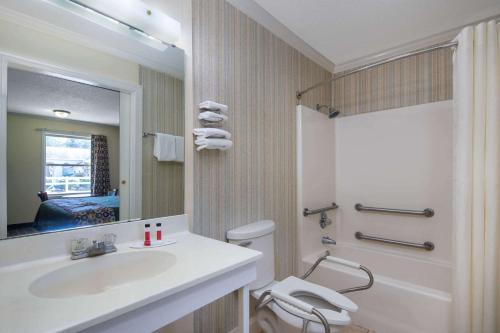 a bathroom with a sink and a toilet and a mirror at Travelodge by Wyndham Orangeburg in Orangeburg