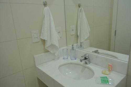 Baño blanco con lavabo y espejo en LOCAR-IN GRAMADO - Loft One Centro II, en Gramado