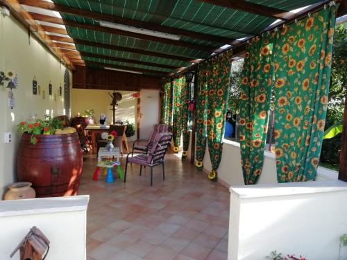 une terrasse avec des rideaux verts, une table et des chaises dans l'établissement casadolcecasalatina, à Latina