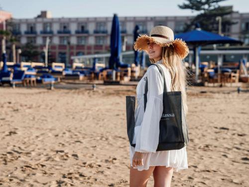 a woman in a hat standing on the beach at Hotel Le Médina Essaouira Thalassa sea & spa – Mgallery in Essaouira