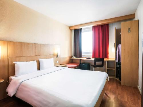 カザンにあるIbis Kazan Hotelの大きなベッドとデスクが備わるホテルルームです。