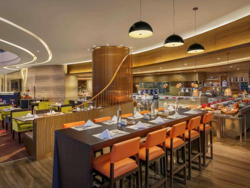 a restaurant with a long table with orange chairs at Novotel Ahmedabad in Ahmedabad