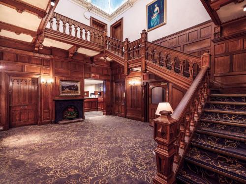 an ornate staircase in a room with a fireplace at Mercure Bradford, Bankfield Hotel in Bradford